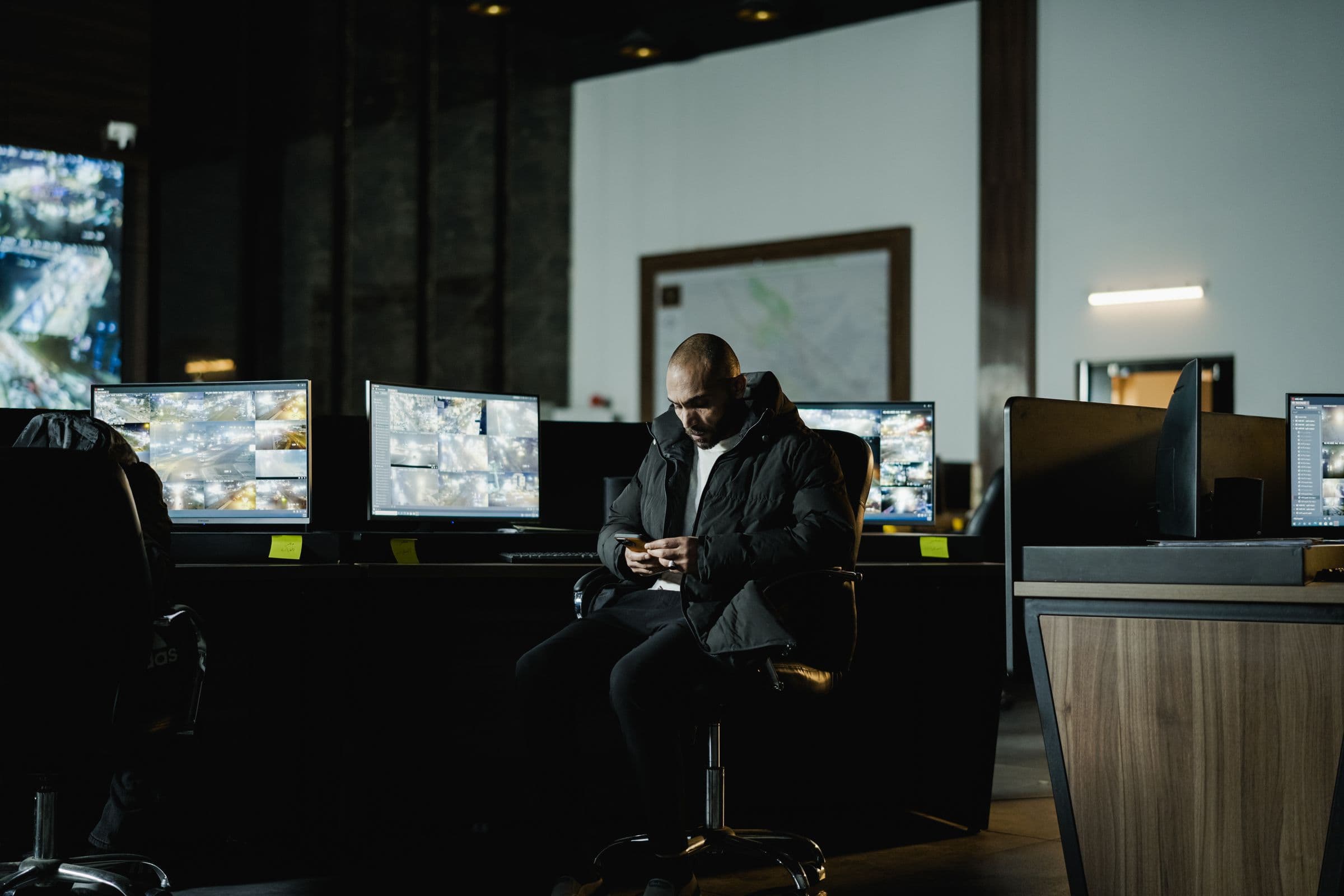 A security operations room, monitors showing live camera feeds.